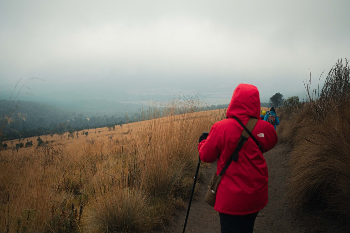 Bild von Ali Alcántara auf Pexels: Wanderer mit Regenjacke auf einem moorigen Bergpfad in Irland