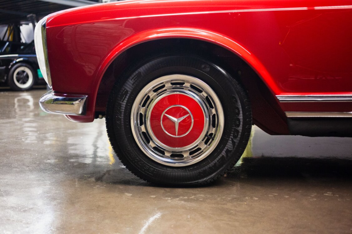 Bild von Deybson Mallony auf Pexels: Nahaufnahme eines roten Oldtimers mit sichtbar montiertem Vorderreifen und Radkappe in einer Garage