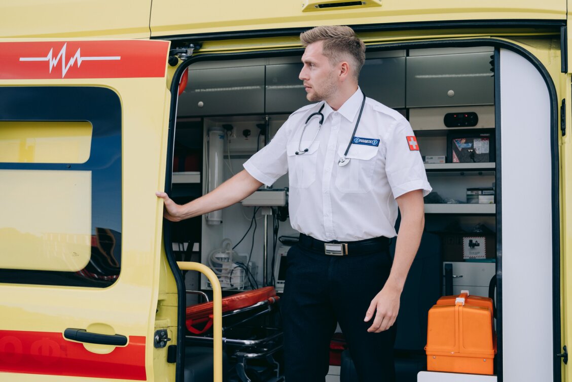 Bild von Mikhail Nilov auf Pexels: Sanitäter neben einem Rettungswagen mit medizinischer Ausrüstung, einsatzbereit für Notfälle